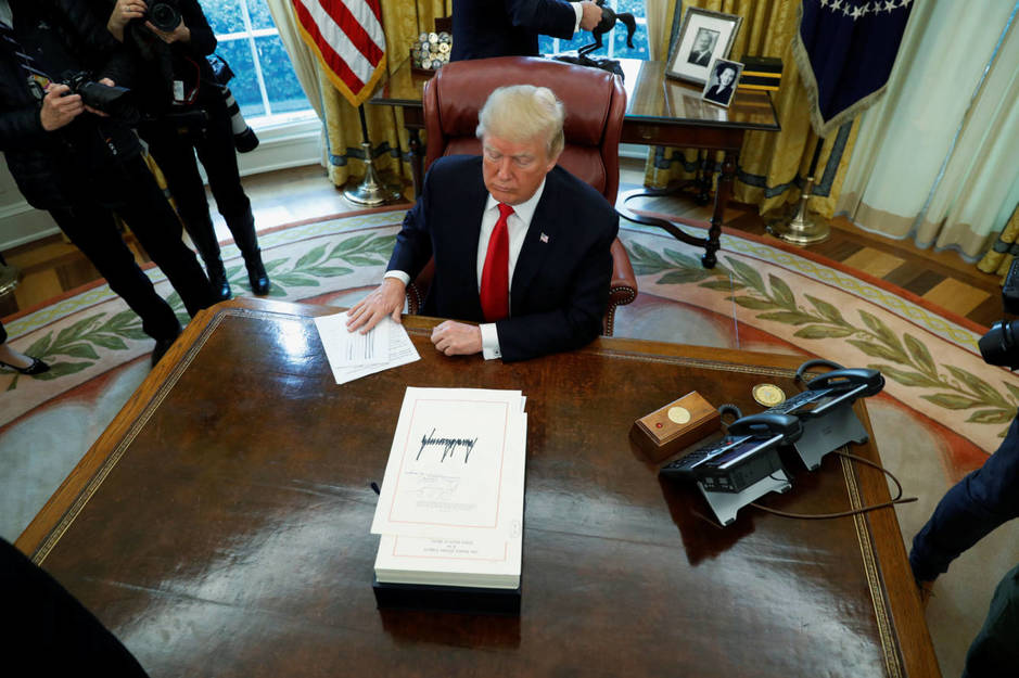 El presidente estadounidense Donald firma una ley ante la prensa en el Despacho Oval, el 22 de diciembre de 2017. (Reuters)
