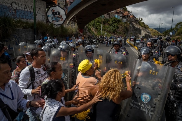 Un grupo de personas protesta frente a miembros de la Policía Nacional Bolivariana (PNB) en Caracas (EFE/Miguel Gutiérrez)