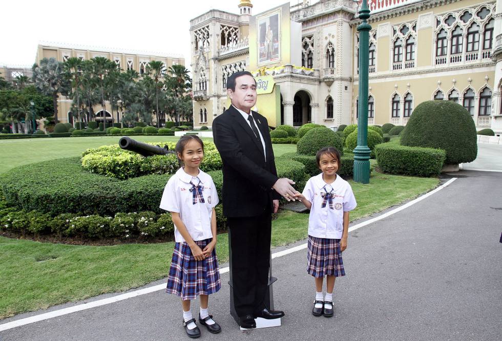 Niños en la sede del gobierno tailandés posando junto al recortable del primer ministro.