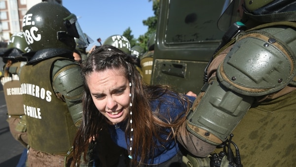 Una joven es detenida por la policía durante las protestas en Santiago. (AFP)