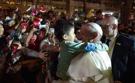 El Papa Francisco abrazando a un niño mientras es recibido por una multitud de fieles a su llegada a la sede de la Nunciatura Apostólica en Lima, Perú.