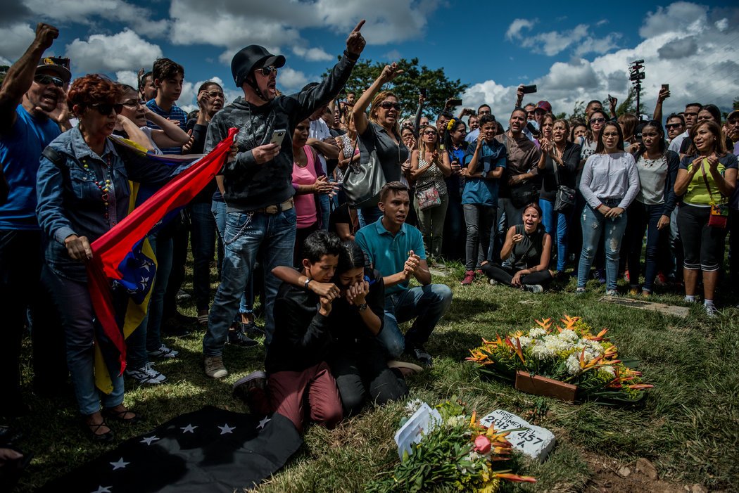 Nicol Díaz, de 17 años, a la derecha, y José Díaz, de 13, al centro, lloran sobre la tumba de su padre, José Alejandro Díaz Pimentel, un rebelde asesinado junto con Pérez en un enfrentamiento con fuerzas gubernamentales. Credit Meridith Kohut para The New York Times