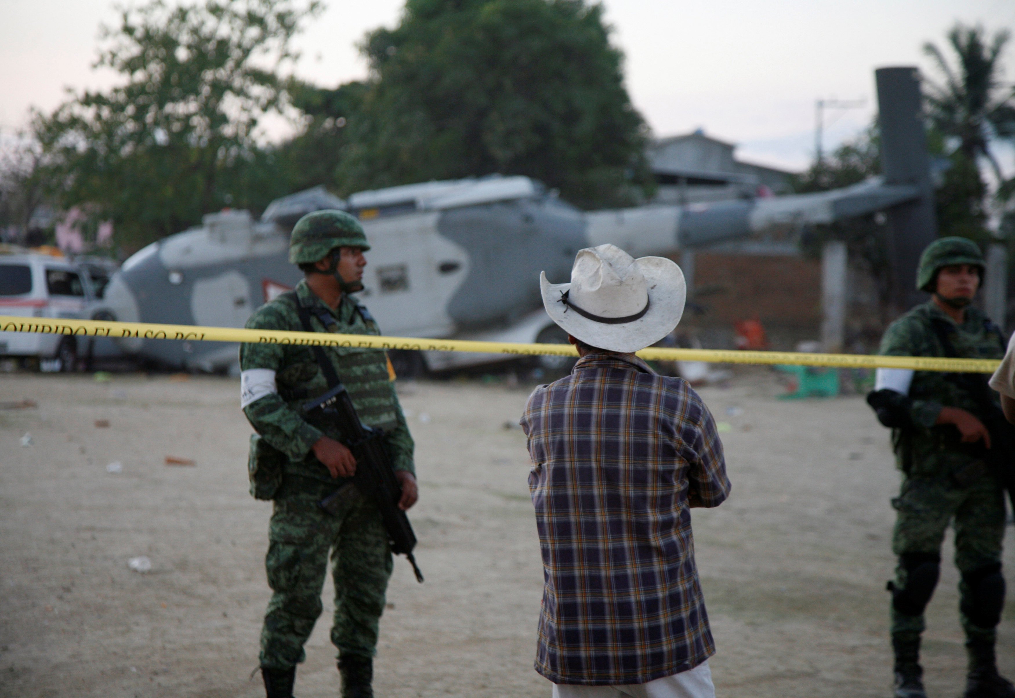 Soldiers stand guard next to a military helicopter, carrying Mexico