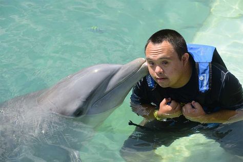 Un joven con síndrome de down que posa junto a un delfín en Mérida (México).
