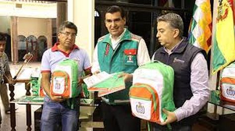 El alcalde de Cochabamba, José María Leyes, y funcionarios muestras una de las mochilas escolares.