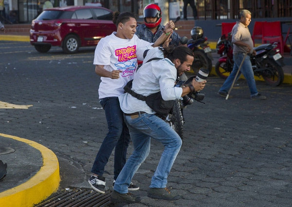 Un miembro de la juventud sandinista forcejea con el reportero gráfico de la agencia de noticias AP Alfredo Zuniga durante las protestas en contra de las reformas del Instituto Nicaragüense de Seguridad Social (INSS), en Managua (EFE/Jorge Torres)