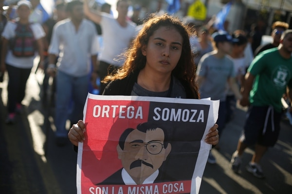 Una manifestante marcha con un cartel que compara al presidente Daniel Ortega con el dictador Anastasio Somoza (REUTERS/Jorge Cabrera)