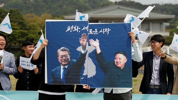 Estudiantes con posters del presidente surocoreano Moon Jae-in y del dictador norcoreano Kim Jong-un durante una manifestación a favor de la reunificación de las dos Coreas (Reuters)