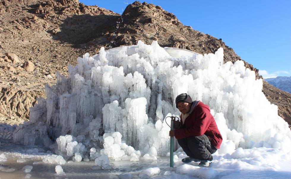 Un trabajador posa junto a una estupa de hielo en proceso de construcción.