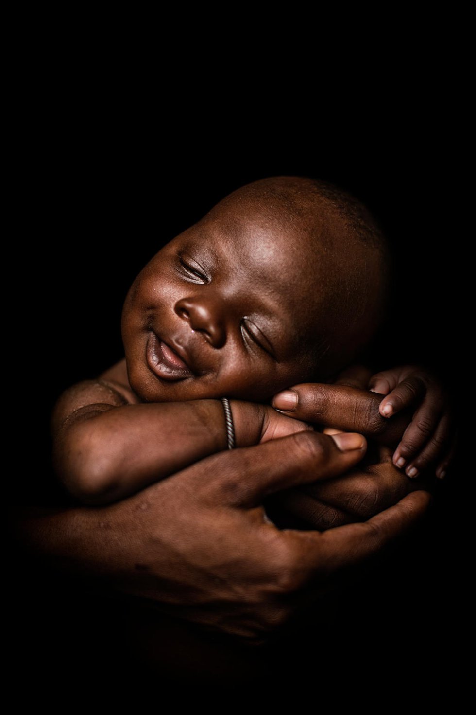 Youssouf Sanogo. Malí. Con 24 días, duerme acunado por su madre el 8 de marzo de 2018 en el Centro de salud pública de Koumatou (Malí). El niño pesó 3,3 kilos al nacer, pero estaba sano y evitó infecciones ya que el centro de salud disponía de agua potable. Youssouf es el primer hijo de Hawa Diawara, de 18 años. "Todo salió bien. Llegué al centro de salud cuatro días antes de dar a luz. Sentí un fuerte dolor en el abdomen, pero luego el parto fue rápido. Después del nacimiento, me lavaron con agua no contaminada. Espero que Youssef me apoye hasta que muera y que crezca sano. Una buena higiene es crucial para asegurarse de que lo haga. El agua limpia, como la que uso en mi casa, la misma que la del hospital, lo ayudará a ir a la escuela". 