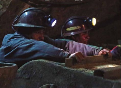 Dos trabajadores mineros empujan un carro.