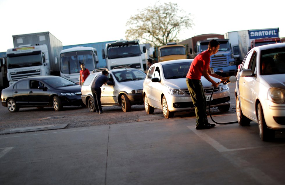 En el estado de Sao Paulo, la gran terminal petrolera de Ribeirao Preto volvió a funcionar después de que los camioneros levantaran el bloqueo. En la imagen, un empleado de una estación de servicio echa gasolina en un vehículo en Brasilia (Brasil), el 29 de mayo de 2018.