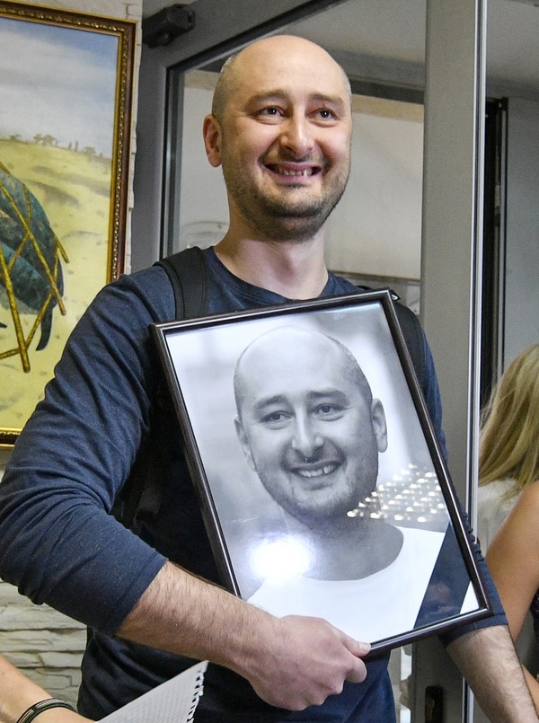 Babchenko con el retrato que sus compañeros habían colgado en la redacción del canal ATR TV tras la noticia de su muerte (AFP / Genya SAVILOV)