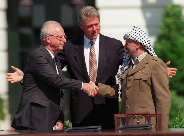 El Primer Ministro de Israel Yitzhak Rabin y el lider de la OLP Yasser Arafat, right, se dan la mano bajo la mirada de Bill Clinton, en la ceremonia para la firma de los acuerdos de Oslo el 13 de septimebre de 1993, en Washington (AP Photo/Ron Edmonds)