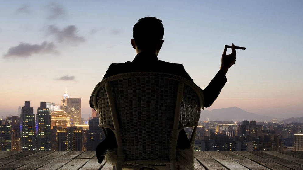 Foto: Un hombre hecho a sí mismo se fuma un puro en un rascacielos. Qué dura es la vida. (iStock)