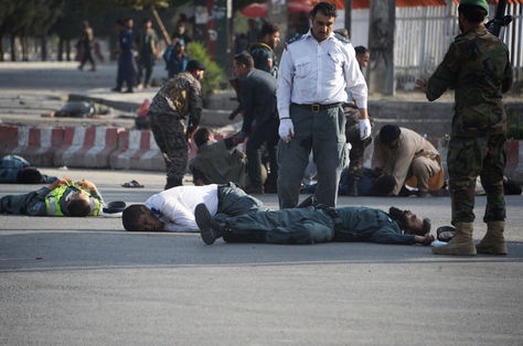 Las fuerzas de seguridad afganas cerca de los cuerpos de las víctimas mientras que otras ayudan a las personas heridas después del ataque suicida en Kabul. Foto: AFP