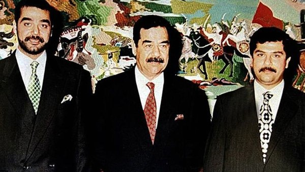 Saddam Hussein flanqueado por sus hijos Uday (izquierda) y Quday (derecha) (AFP)