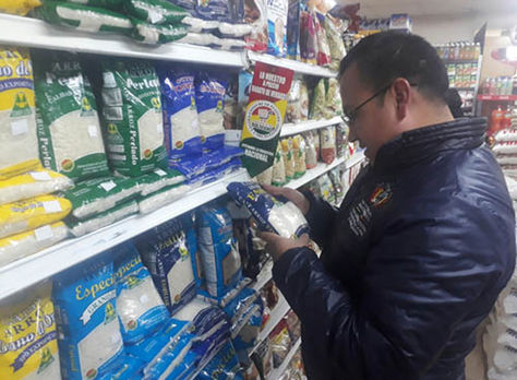 Funcionario del Viceministerio de Defensa de los Derechos del Usuario y del Consumidor revisa paquetes de arroz en un supermercado.