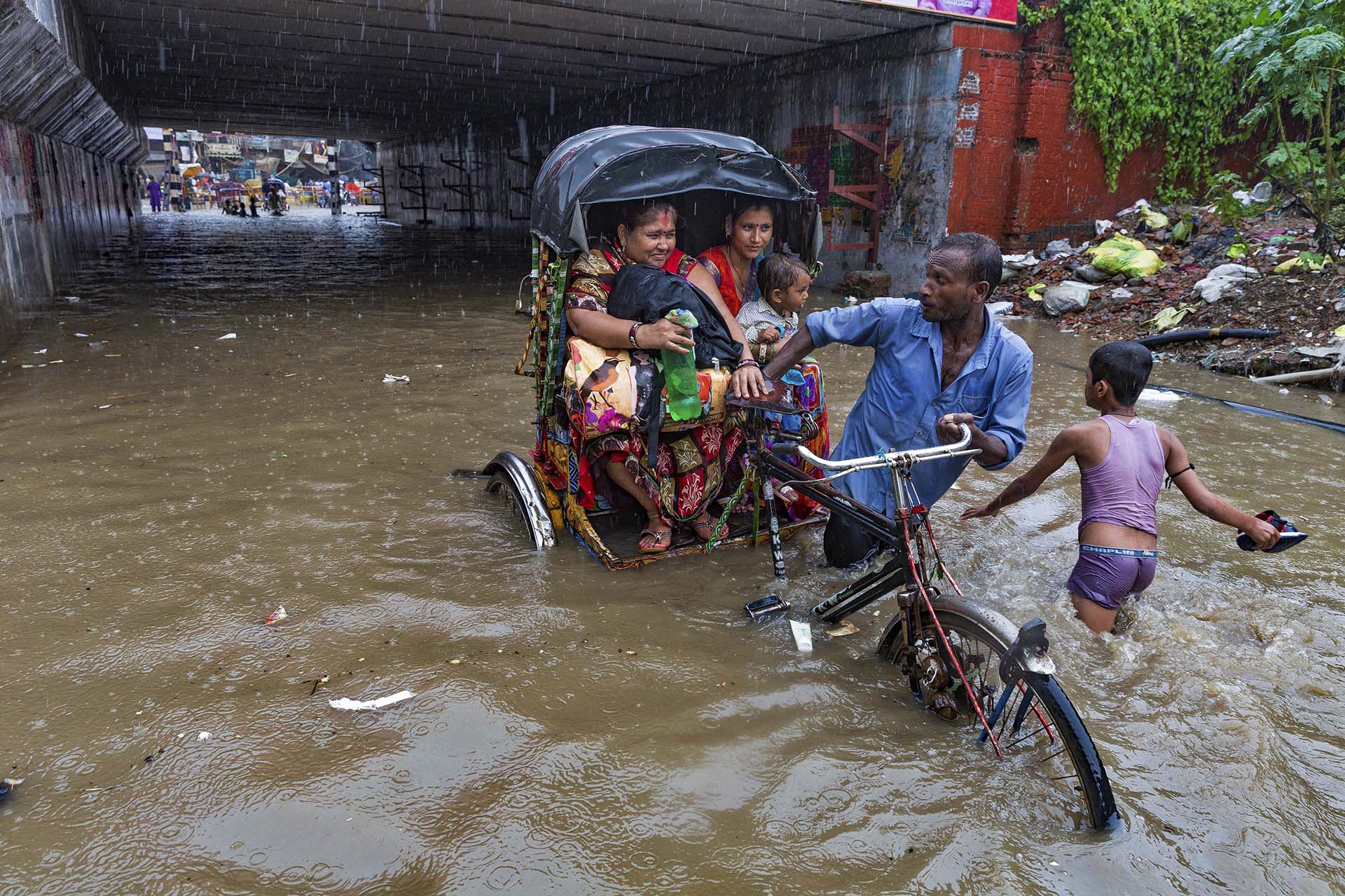 Un hombre transporta a dos mujeres en medio del temporal (AP Photo/Rajesh Kumar Singh)