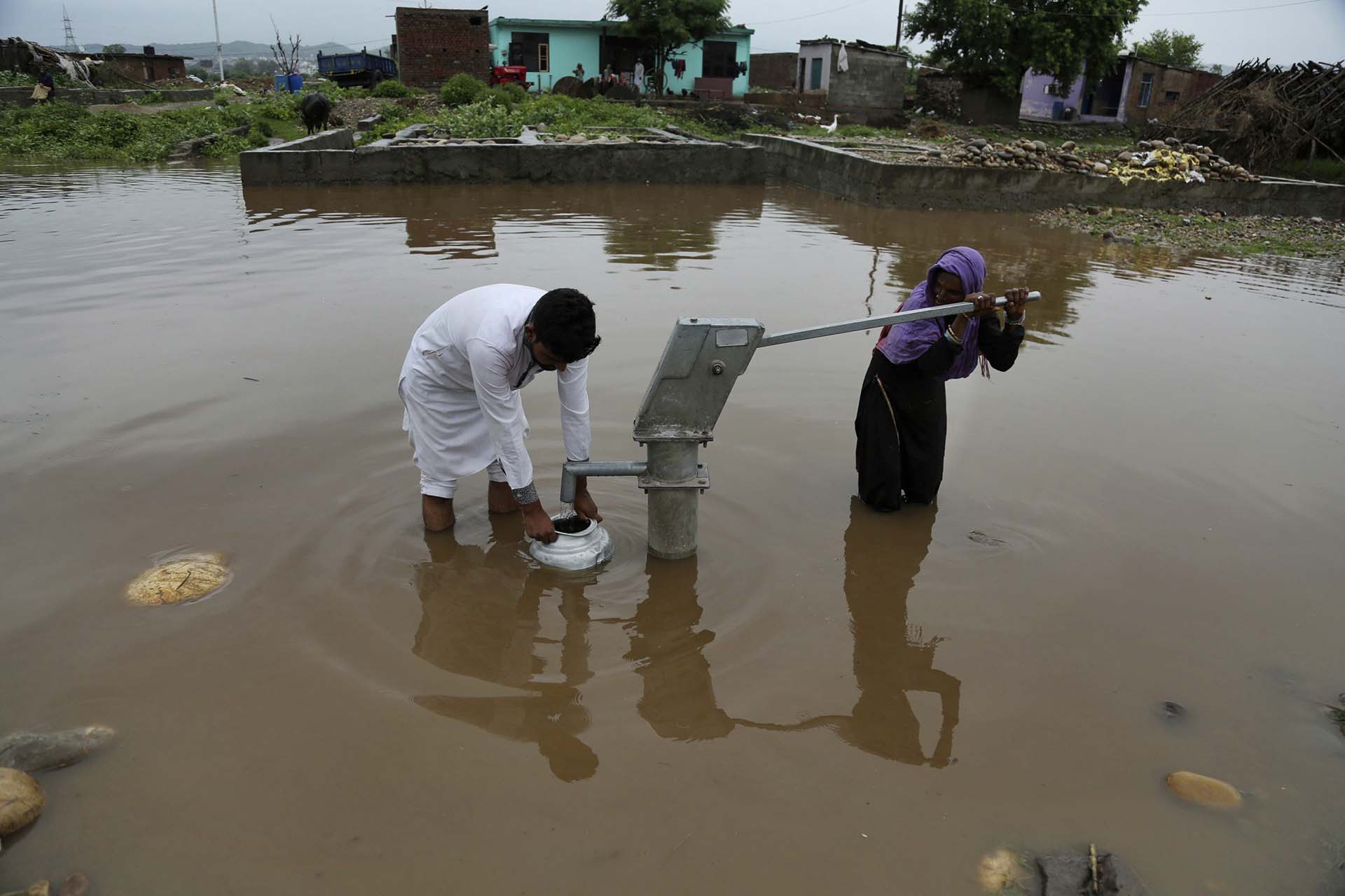 Una pareja recolecta agua potable en Jammu, India (AP Photo/Channi Anand)