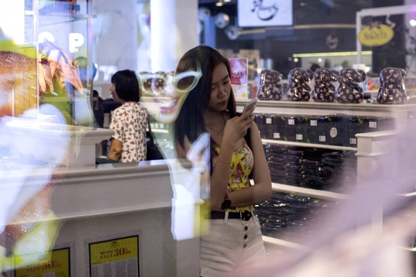 Un joven observa un teléfono inteligente en un centro comercial de Bangkok (Bloomberg / Brent Lewin)