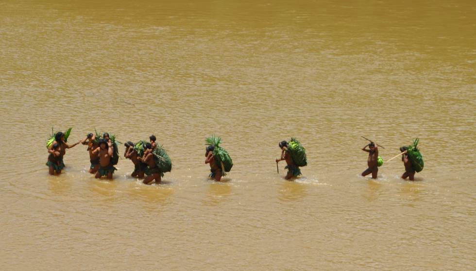 Un grupo de indígenas en aislamiento cruza un río en departamento de Madre de Dios, en Perú. Si tuvieran una afección, habría de ser atendidos en la orilla.rn rn