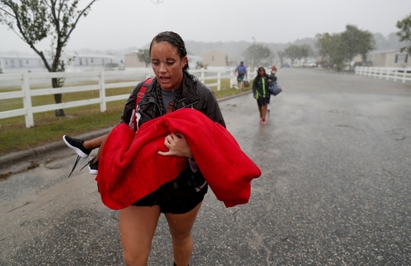 Una mujer carga a un menor durante las evacuaciones en Carolina del Norte (Reuters)