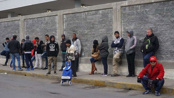 Un grupo de ciudadanos cubanos espera en la línea fronteriza de Nuevo Laredo (México) con territorio estadounidense (EFE)