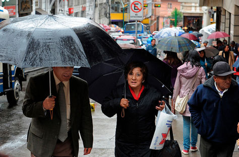 Personas se cubren de una lluvia en La Paz. Foto: archivo La Razón