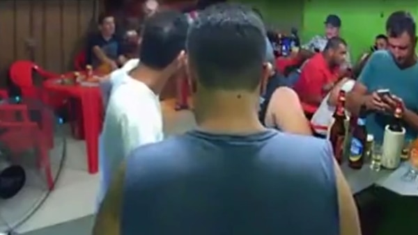 El hombre estaba parado al lado de la barra, revisando su celular