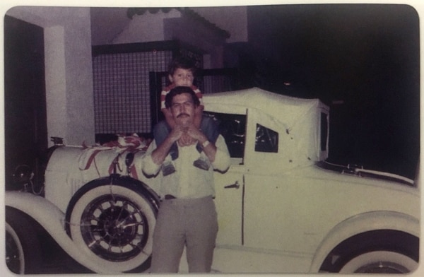 Juan Pablo sobre los hombros de Pablo Escobar, el día en que el jefe del Cartel de Medellín cumplió 30 años. Detrás, el automóvil que Victoria Henao le regaló para la ocasión (Victoria Eugenia Henao – Editorial Planeta)