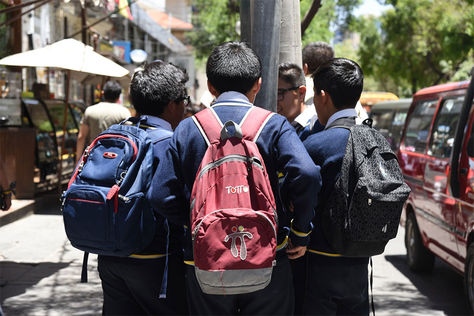Estudiantes caminan con sus útiles escolares por el centro de la ciudad.