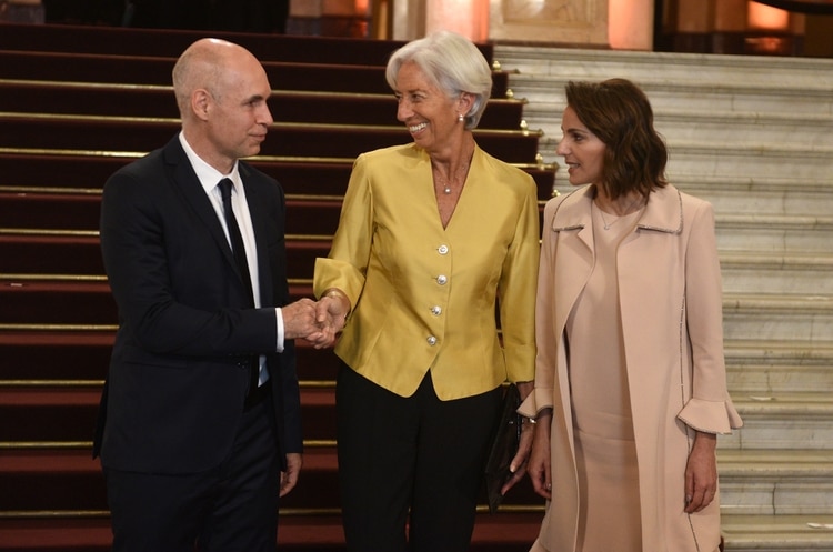 Christine Lagarde participó de la gala del Colón con un look masculino de dos piezas. Una chaqueta en color mostaza con botones plateados completando el look con pantalón recto negro y sobre a tono (Presidencia)