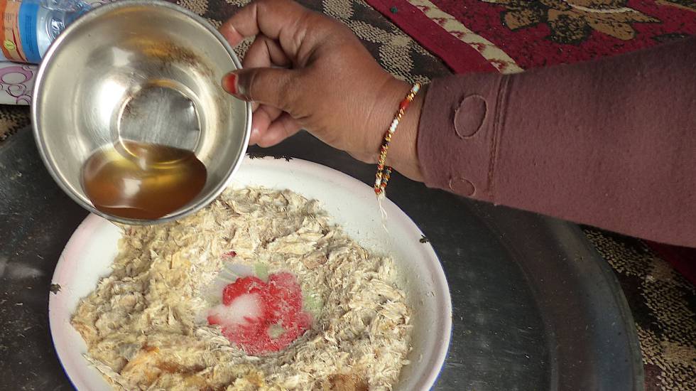 Una mujer sirve un plato de pescado seco, llamado 