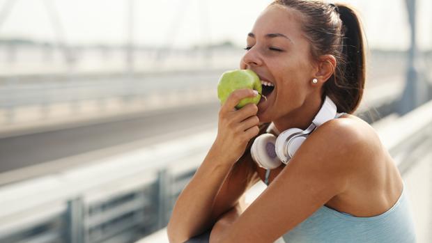 Una mujer, mordiendo una manzana.