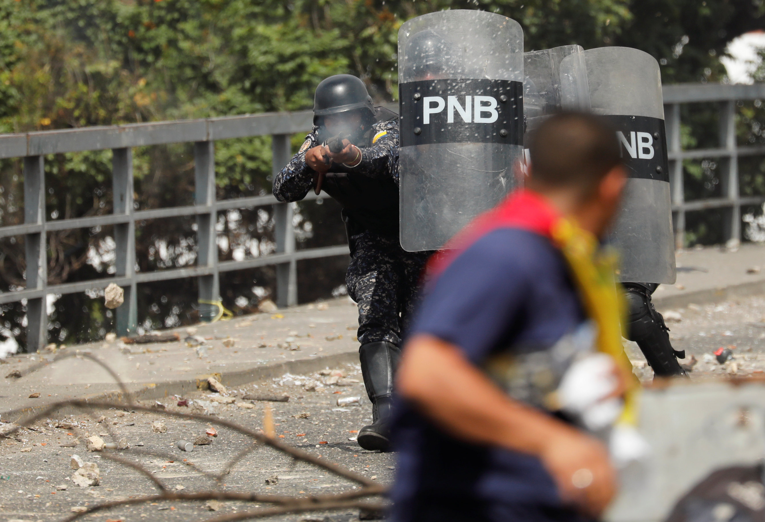 Un miembro de la Policía Nacional Bolivariana dispara balas de goma a los manifestantes en Caracas