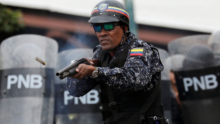 Un miembro de la Policía Nacional Bolivariana dispara a los manifestantes (Reuters)