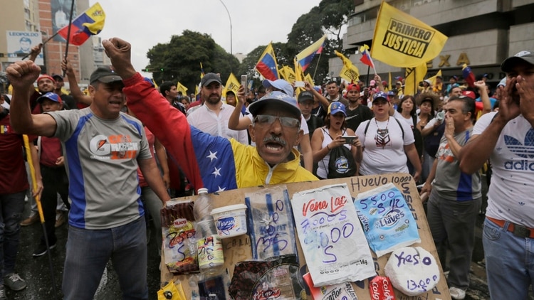Un venezolano muestra el precio de los productos, disparados por la inflación (AP)