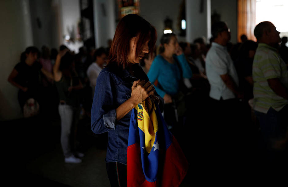Una simpatizante de Juan GuaidÃ³ sostiene una bandera de Venezuela durante una misa en Caracas. (Reuters)
