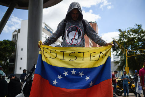 Un hombre sostiene una bandera de Venezuela durante un mitin en Caracas. Foto: AFP