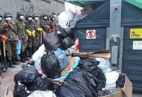 La basura acumulada en una esquina de la zona Miraflores, al fondo los militares que hacen la limpieza.