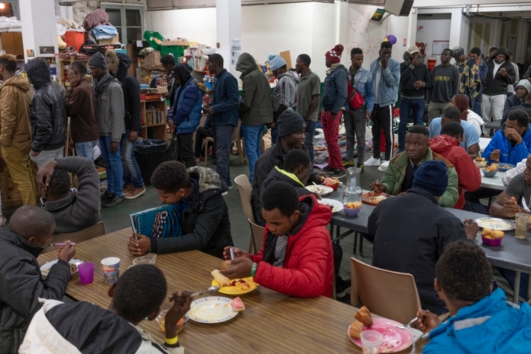 Migrantes hacen fila para cenar. (Samuel Aranda/The New York Times)