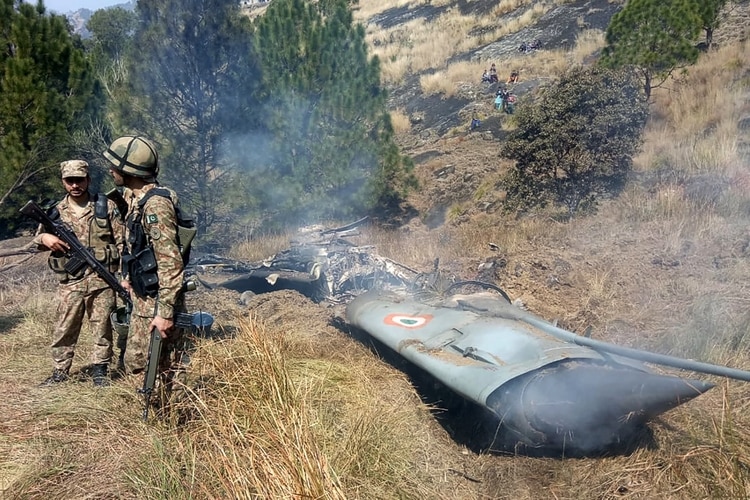 Soldados de Pakistán junto a los restos que, afirman, pertenecen a un avión de la India (AFP)