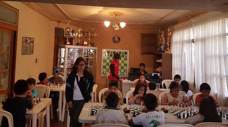 La ajedrecista cochabambina Jessica Molina (de pie) supervisa el juego de los estudiantes de la escuela “Mentes Brillantes”. | Los Tiempos