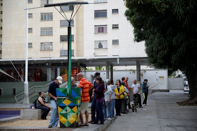 Ciudadanos hacen fila para cargar los celulares en un puesto de energía solar (REUTERS/Carlos Garcia Rawlins)