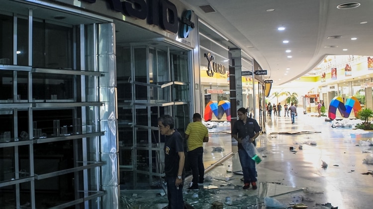 Varias personas observan los daños en locales del centro comercial Sambil el 12 de marzo en Maracaibo (EFE)