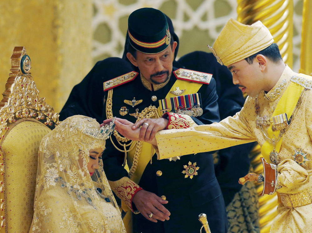 Foto: El sultán de Brunei, Hassanal Bolkiah, sostiene la mano de su hijo para bendecir a su nueva esposa durante la ceremonia en el palacio Nurul Iman. (Reuters)