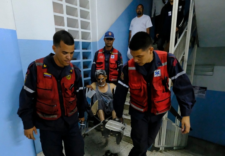 Un hombres asistido por médicod. (Photo by MATIAS DELACROIX / AFP)