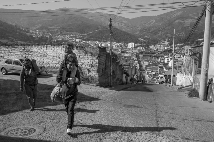Luis lleva a la hija de Hector, Lucianny, por las calles de la ciudad colombiana de Pamplona. El primo de Richard, Antony, los sigue. Fotógrafo: Carlos Villalon / Bloomberg.