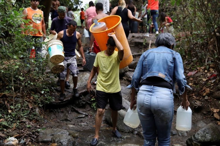 Las personas cargan recipientes para llenar con agua de un río en Caracas, Venezuela, 31 de marzo de 2019. (REUTERS)